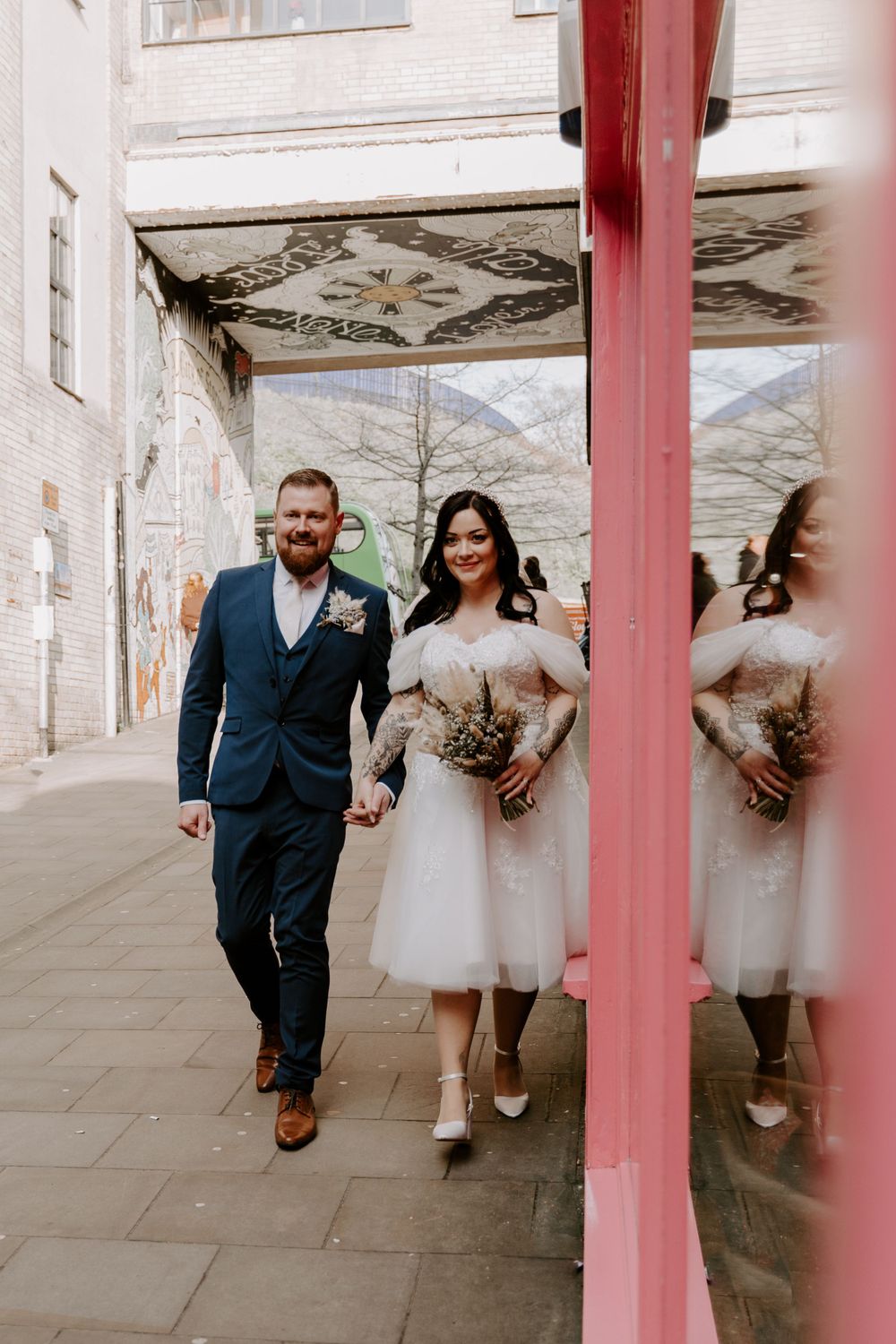 Bride and groom walking outside a Lucy and Yak shop.
