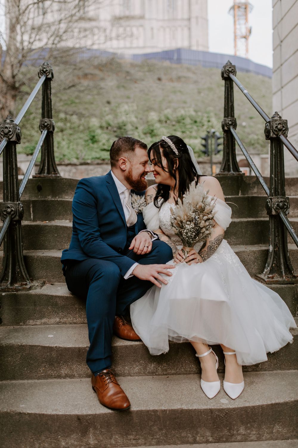 bride and groom sat on some steps in the city centre.