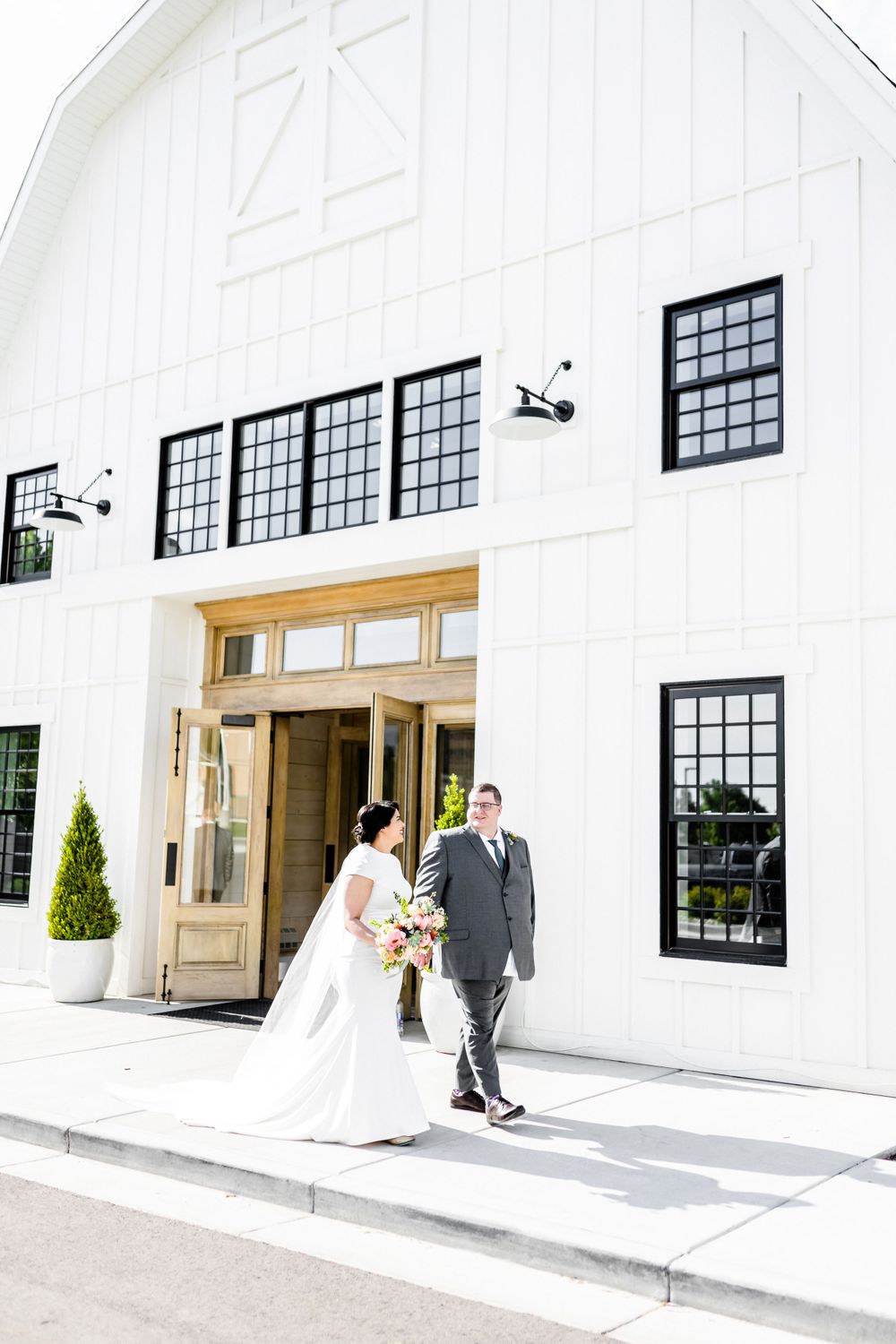 A modern white barn wedding venue with black windows and elegant architectural details.