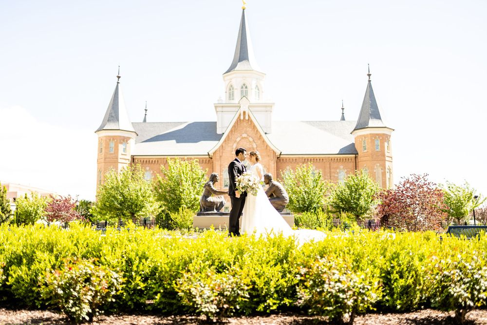 A church spire and steeples photographed against a bright blue sky with landscaping in foreground.
