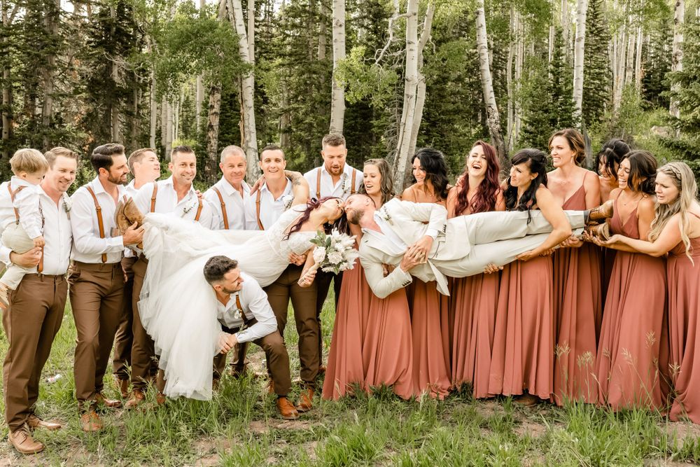 Wedding party in rustic attire posing together against a backdrop of aspen trees.