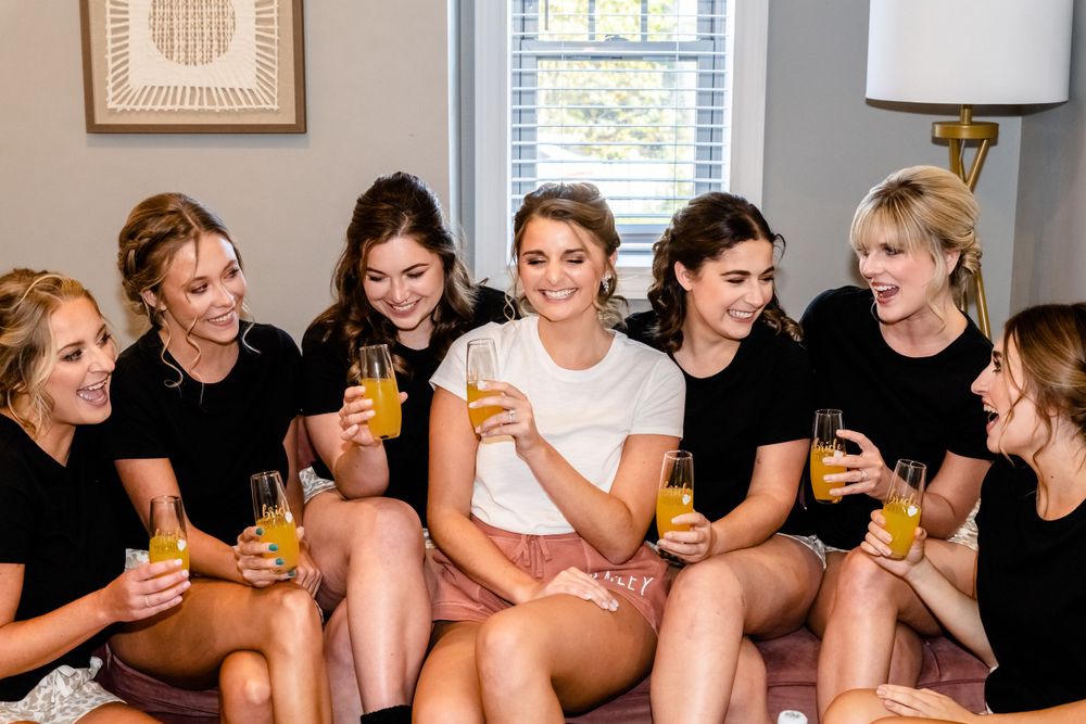Wedding party enjoying drinks and laughter together indoors.