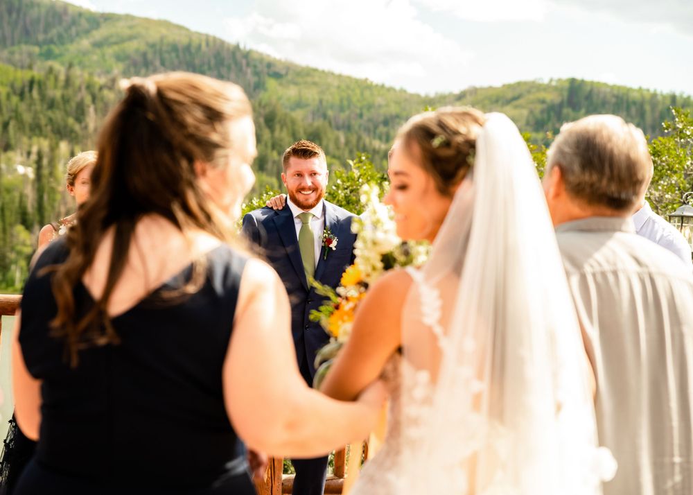 A scenic mountain wedding ceremony with guests gathered outdoors against a natural backdrop.