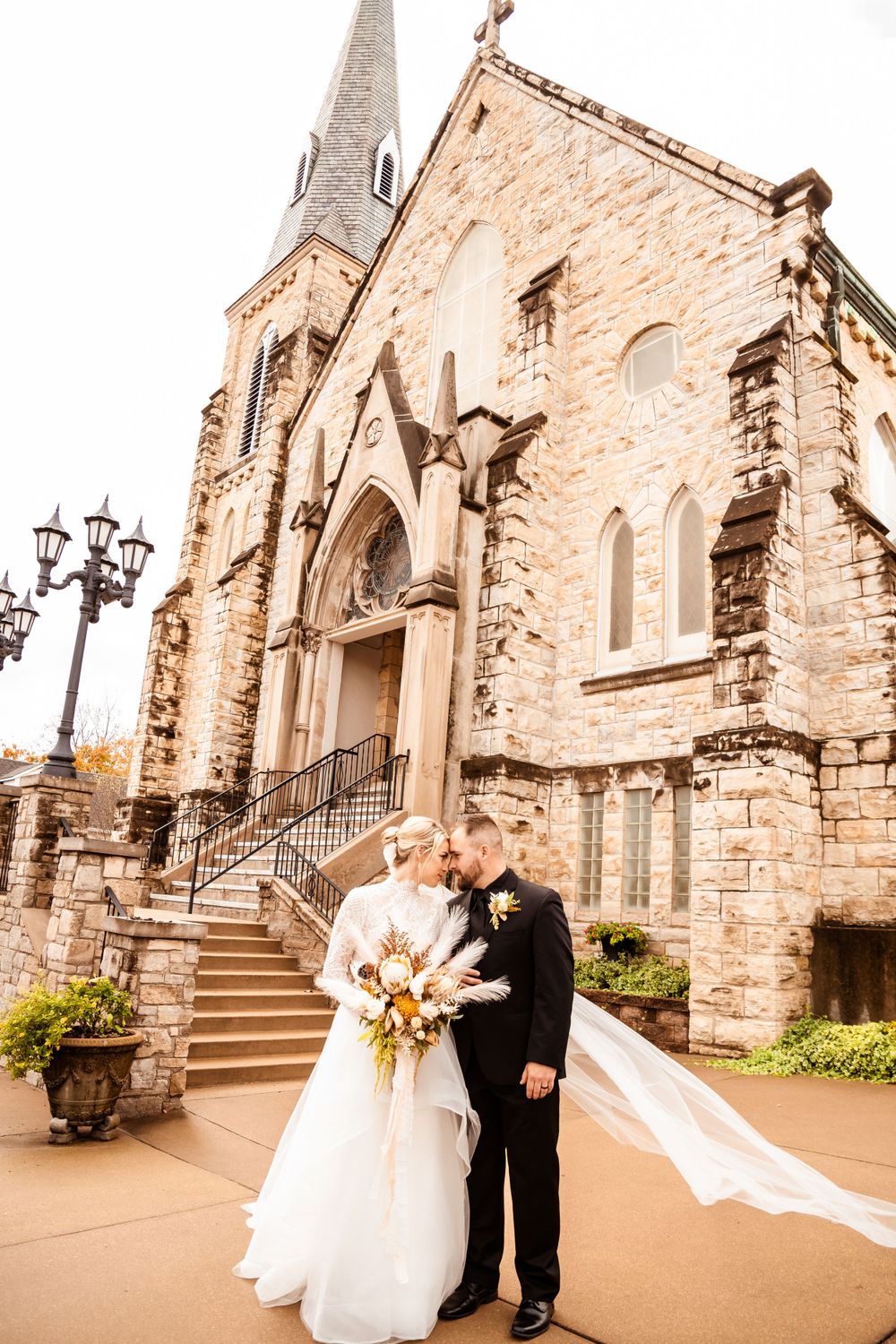 Wedding photos at historic stone church with Gothic architecture and elegant stairs.