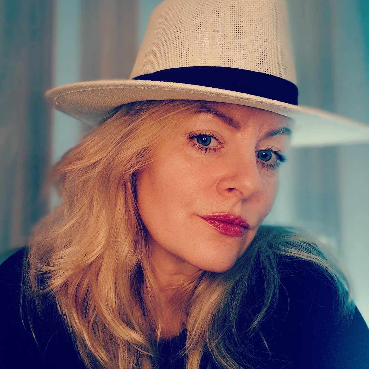Portrait of woman wearing light-colored hat in soft natural light.