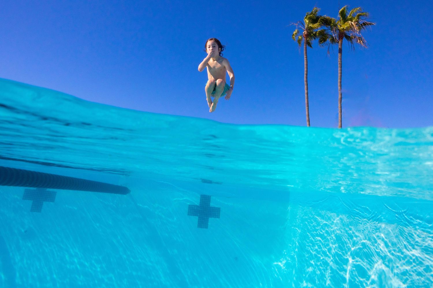 Little kid jumping in pool underwater photo split shot