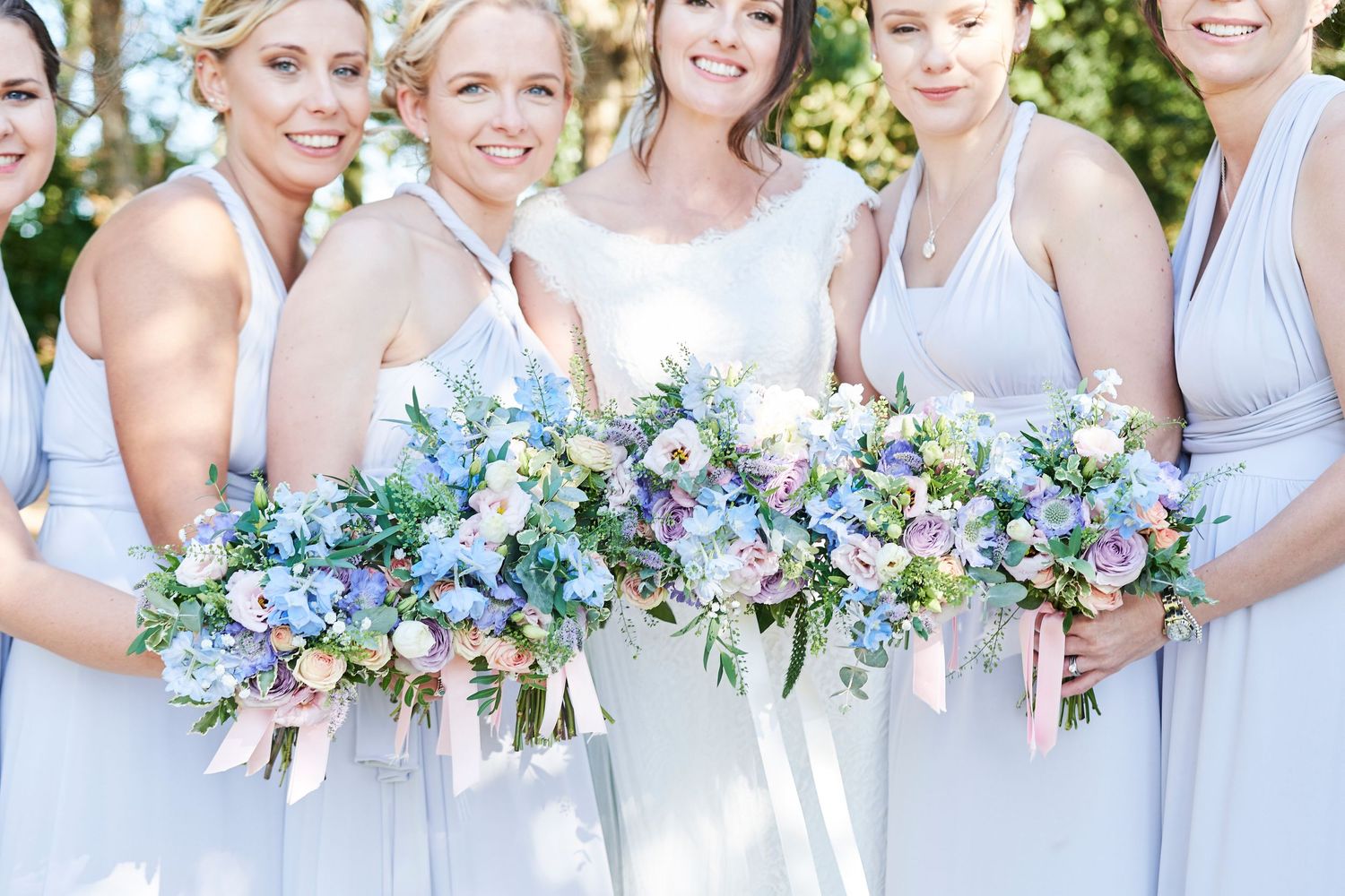 bride and bridesmaids hold their bouquets together at their farm wedding in Norfolk. by Norfolk wedding Photographer