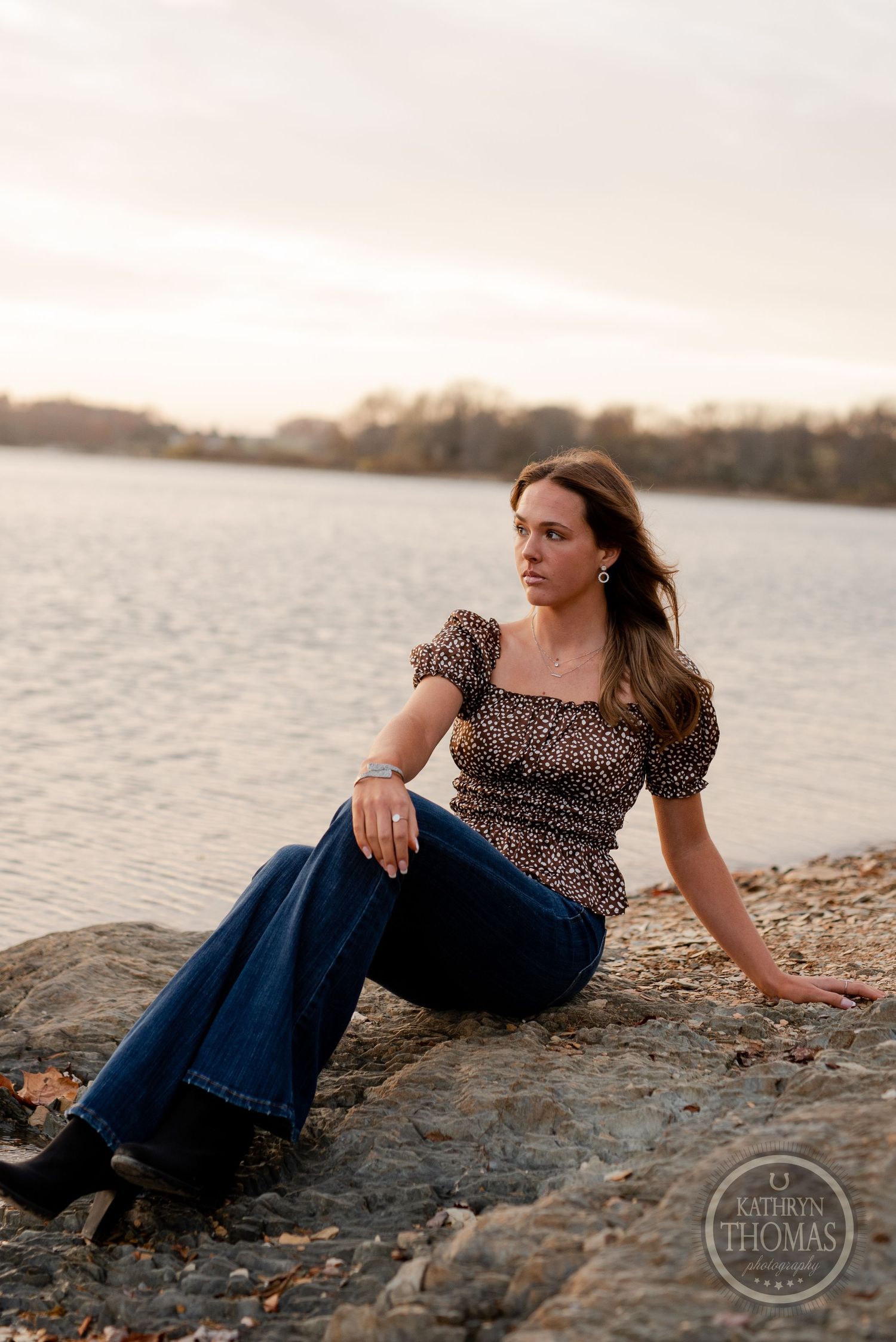 Casual autumn photoshoot on rocky lakeside terrain during sunset.