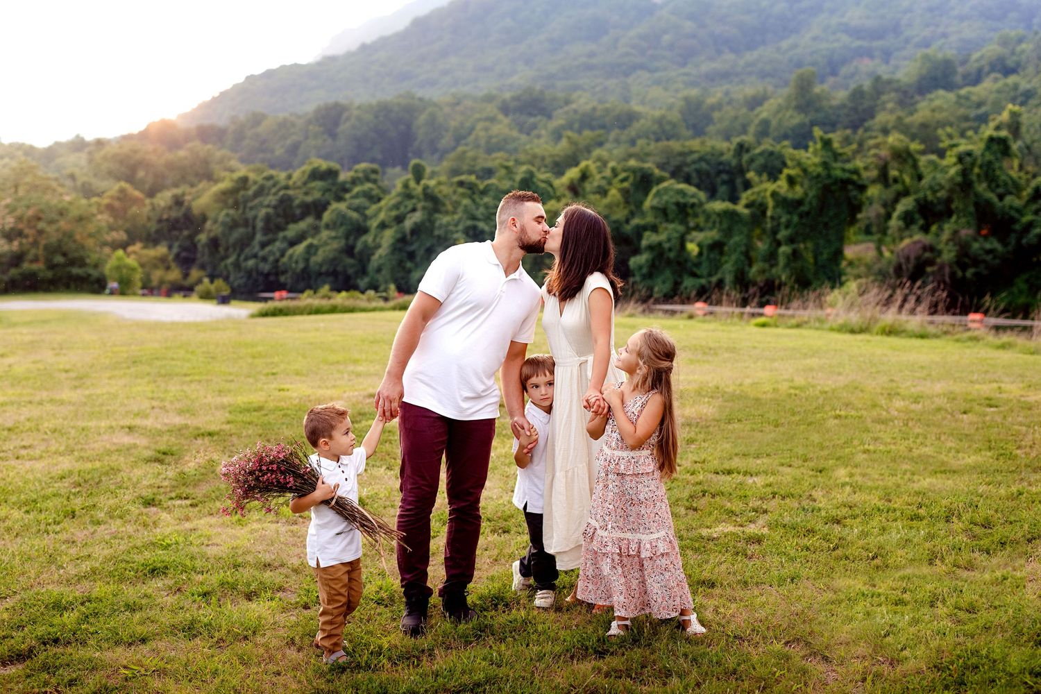 Family sharing tender moment together in sunny mountain meadow at sunset.