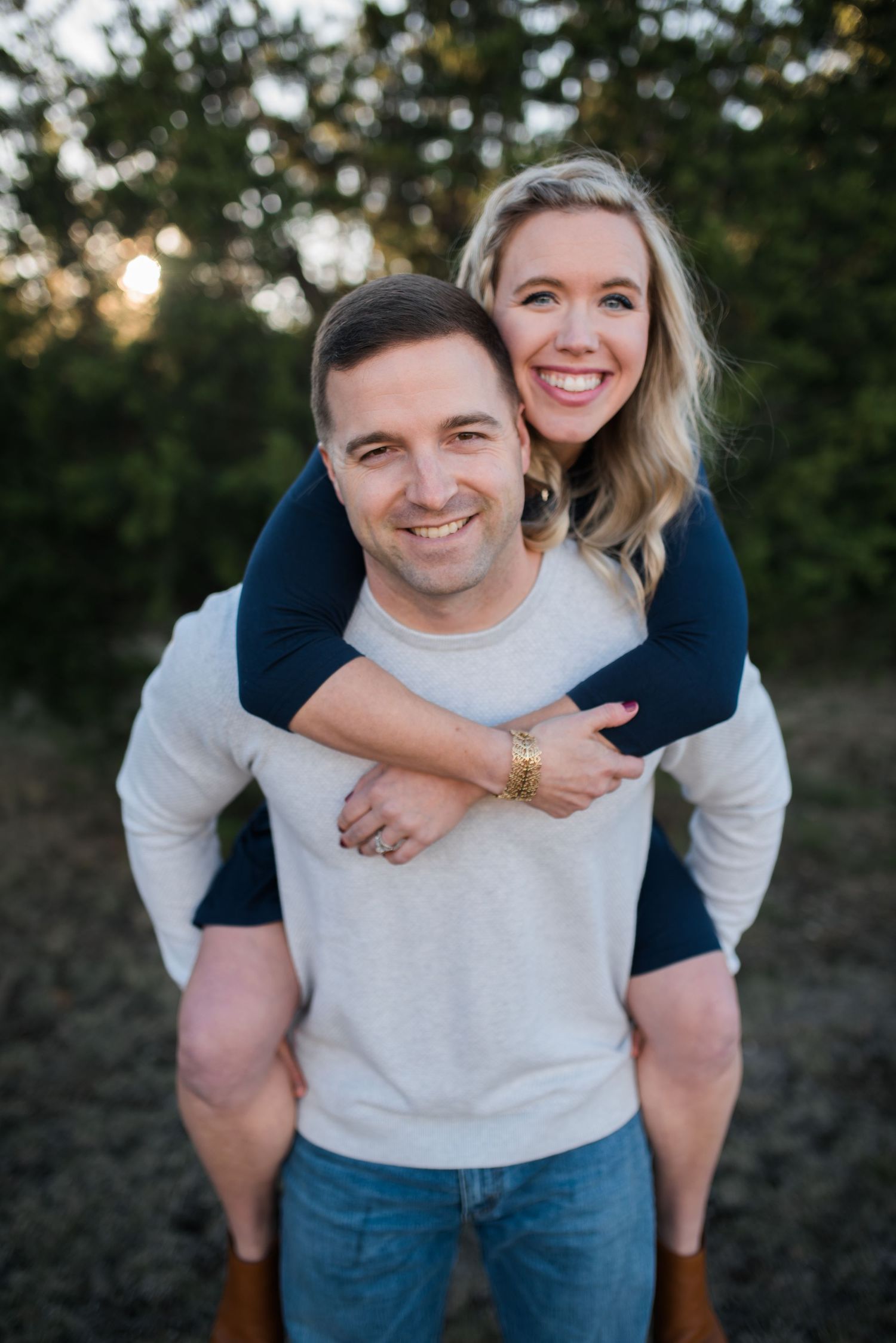 Couple shares playful piggyback ride moment during outdoor sunset photo session.