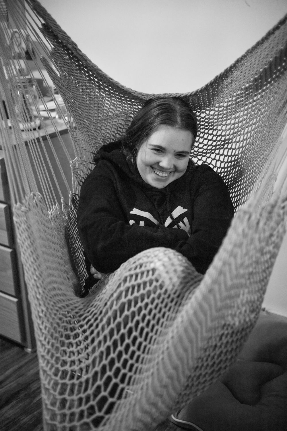 Someone relaxing and laughing in a mesh hammock.
