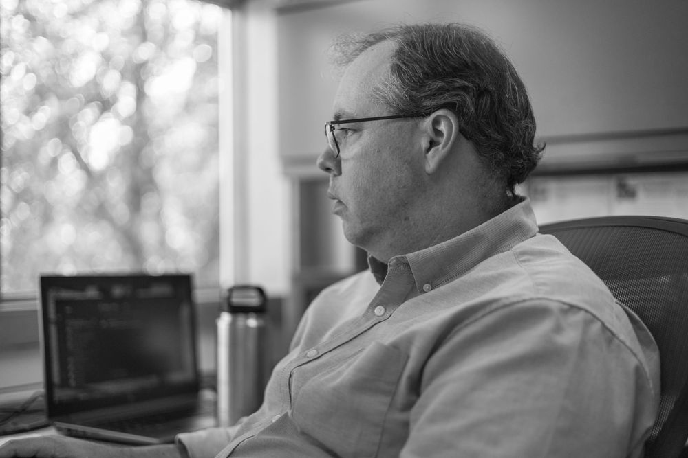 Person sitting at desk viewed from side profile.