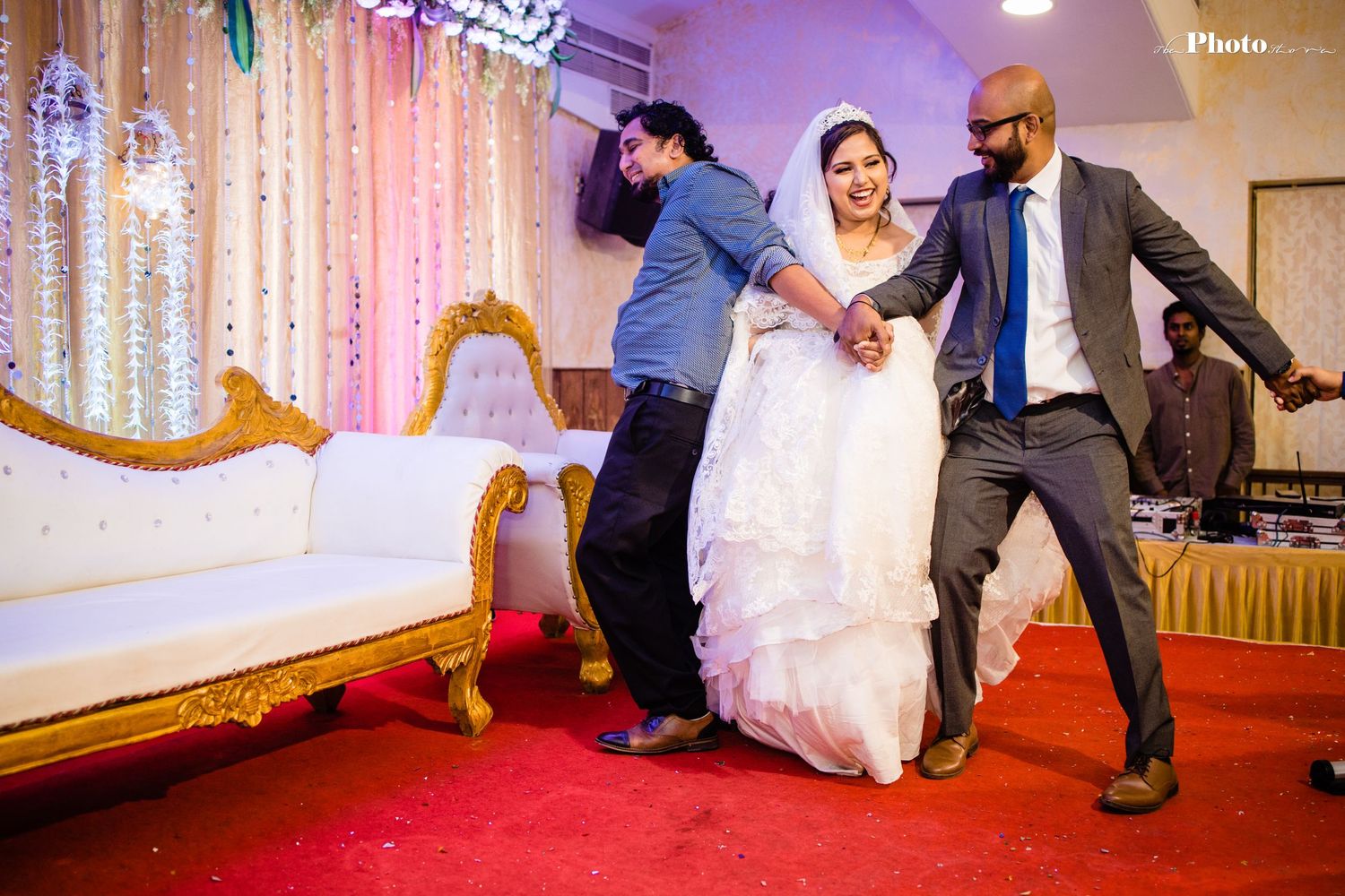 Wedding celebration with bride in white dress dancing with guests against sparkly backdrop.