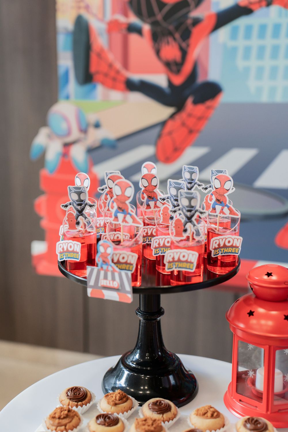 Spider-Man themed party decorations with red cutouts displayed on a black stand.