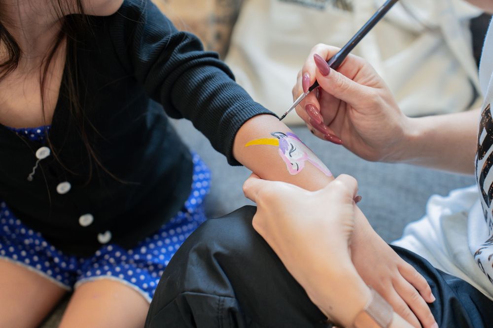 Close-up of face painting being applied to someone's arm.