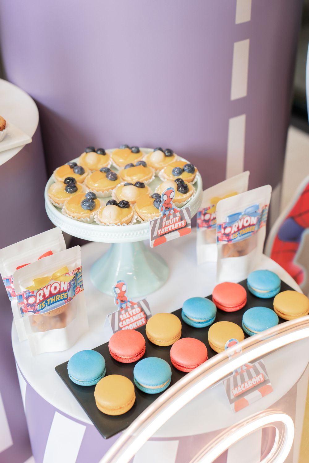 Dessert table with colorful macarons and blueberry topped pastries at a party.