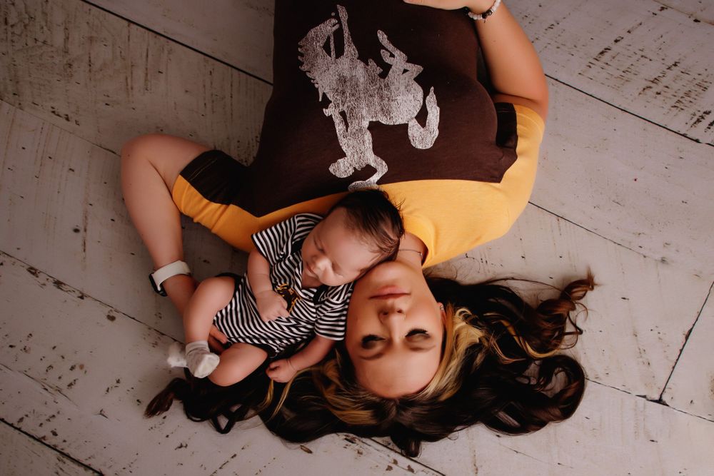 Overhead view of person in yellow shirt laying on wooden floor.
