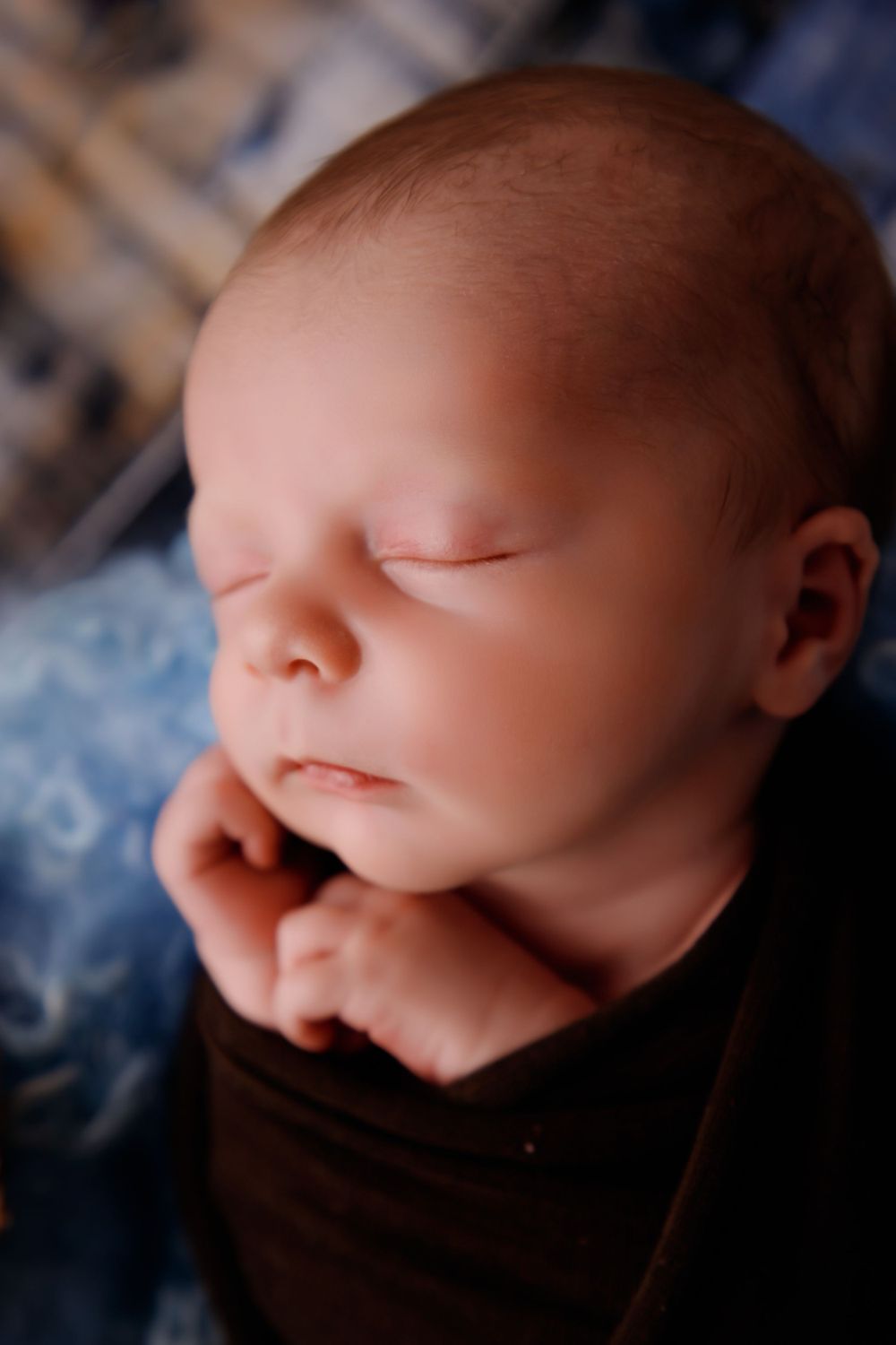 Close-up of peaceful sleeping newborn against blue textured background.
