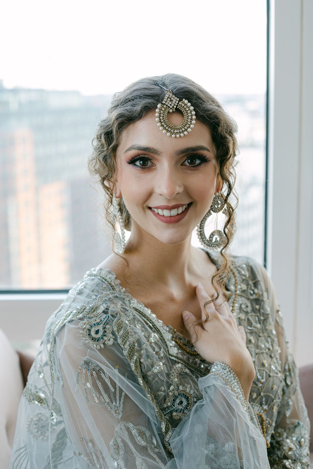A bridal portrait featuring a traditional Indian tikka headpiece and embellished silver gown.
