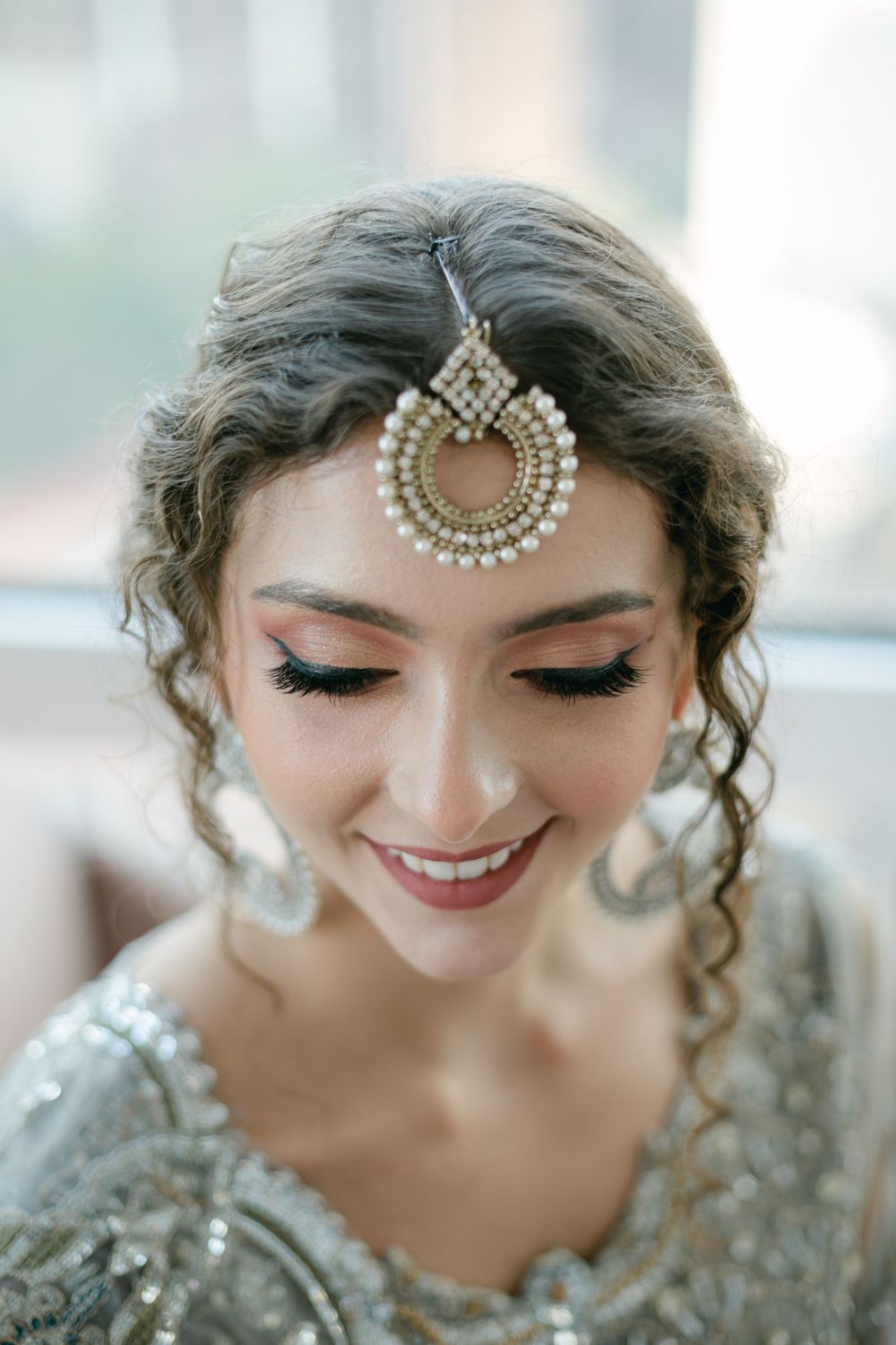 A close-up shot highlighting intricate pearl headpiece and delicate silver bridal makeup.