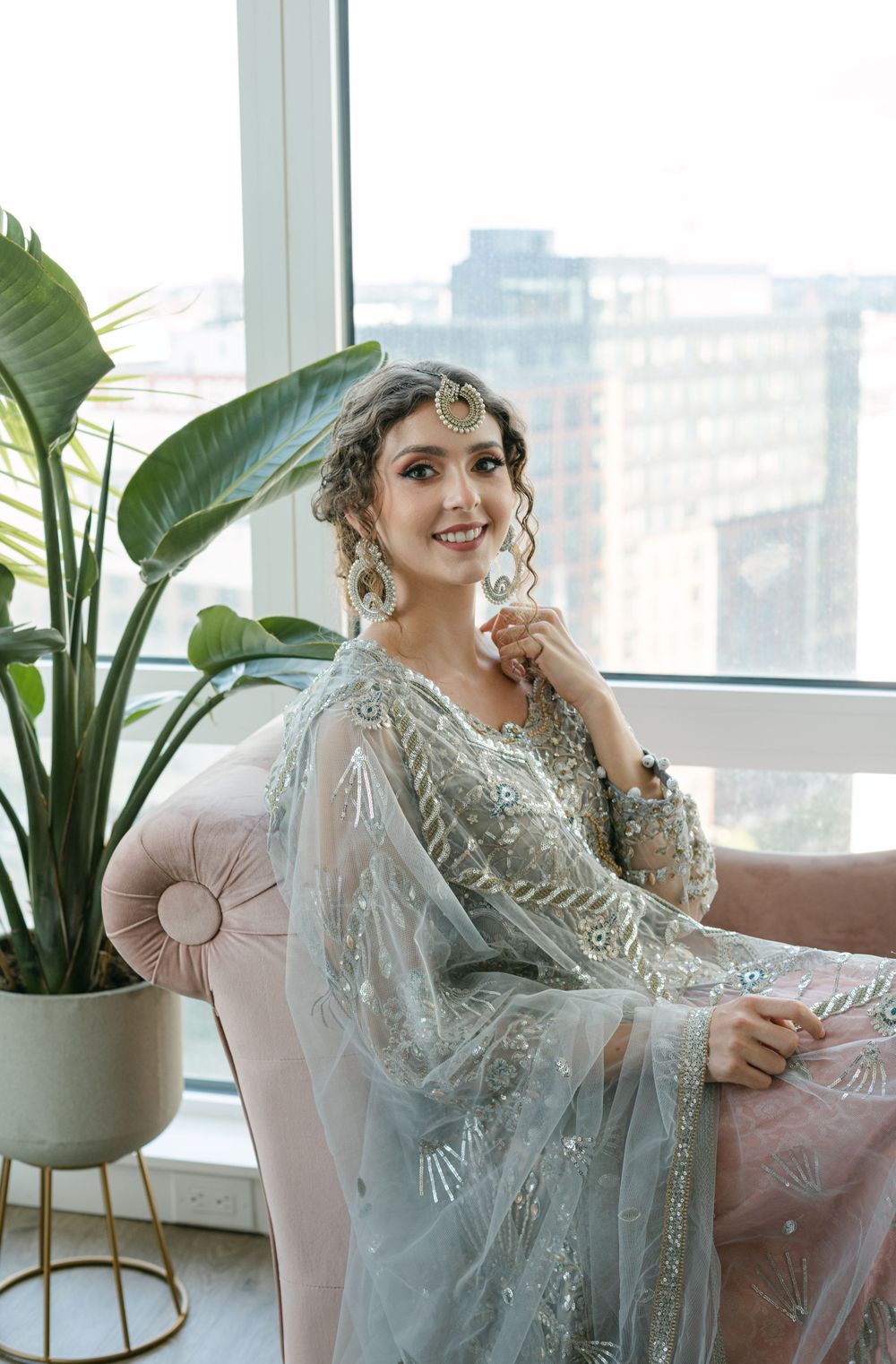 Luxurious silver embroidered dress photographed in a modern apartment with city views.