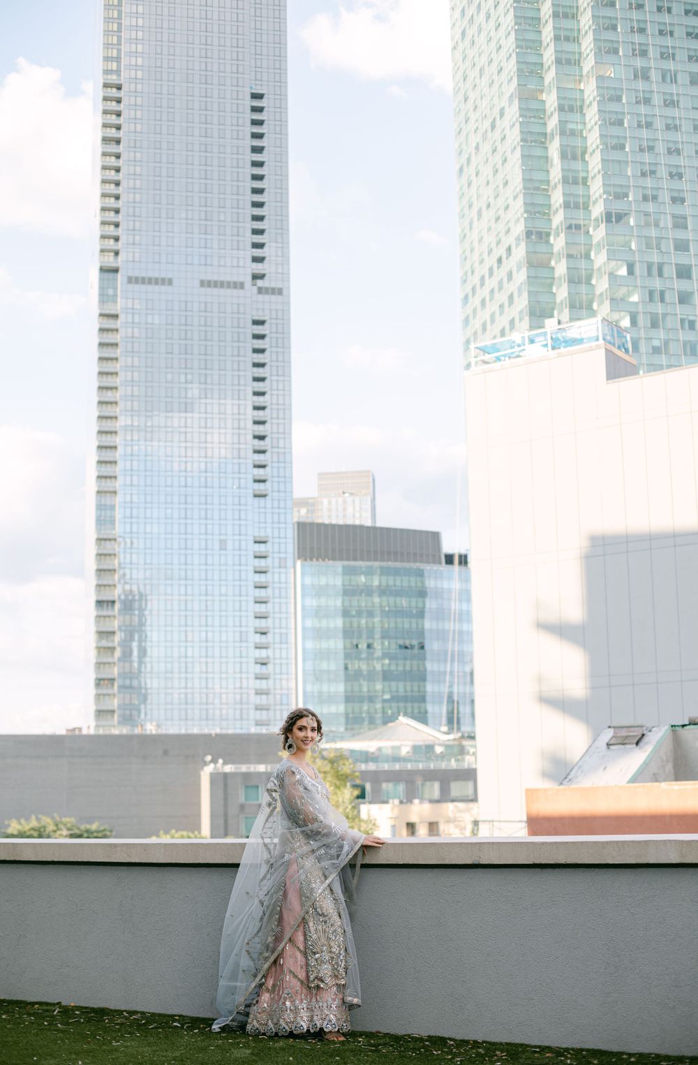 Formal silver dress photographed against modern urban architecture and sky.