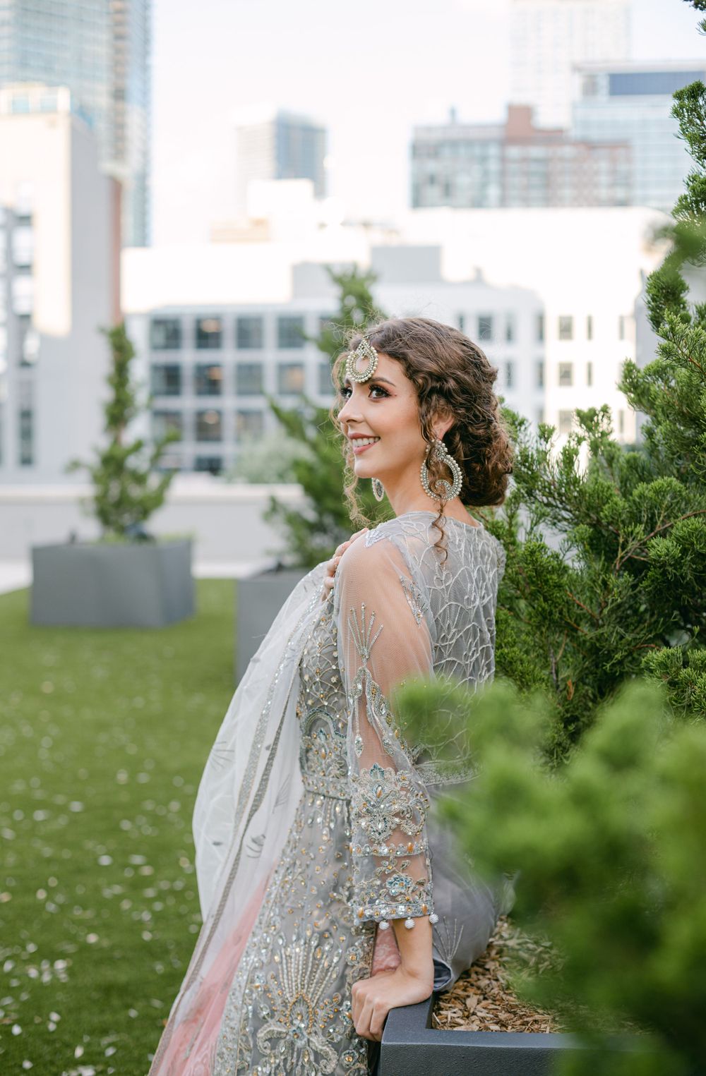 Ethereal silver embroidered gown captured in urban rooftop garden setting.