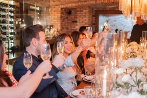 Guests enjoying a celebration dinner at long tables with candlelight and floral arrangements.