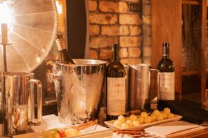Rustic candlelit dining table with wine bottles and glasses in a brick-walled restaurant setting.