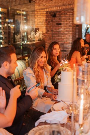 A celebratory dinner gathering with sparklers and cake in a rustic brick-walled venue.