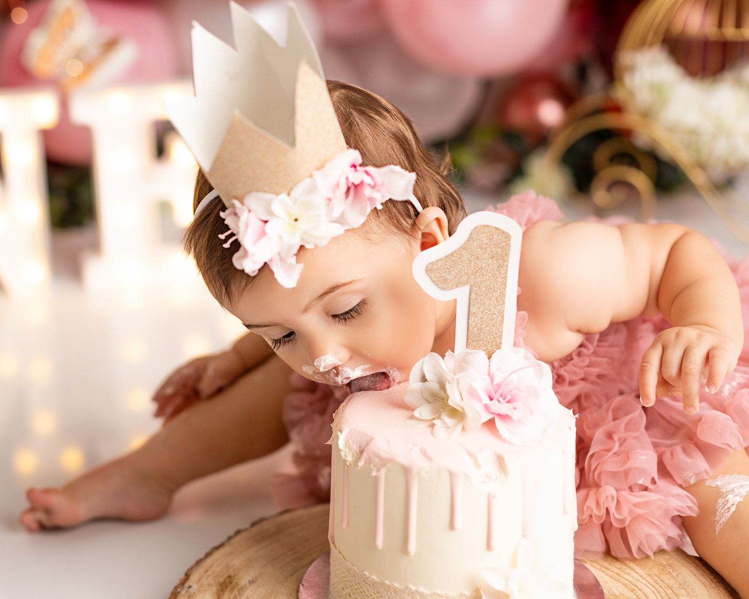 First birthday celebration setup with a white cake topped with a crown and pink decorative details. springdfield lakes.