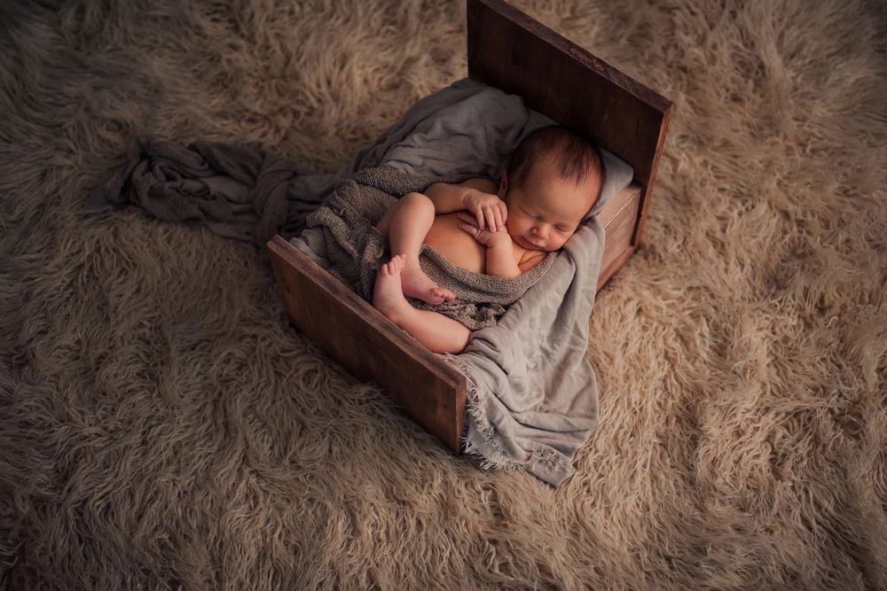Cozy newborn portrait session on textured grey fur with natural lighting.
