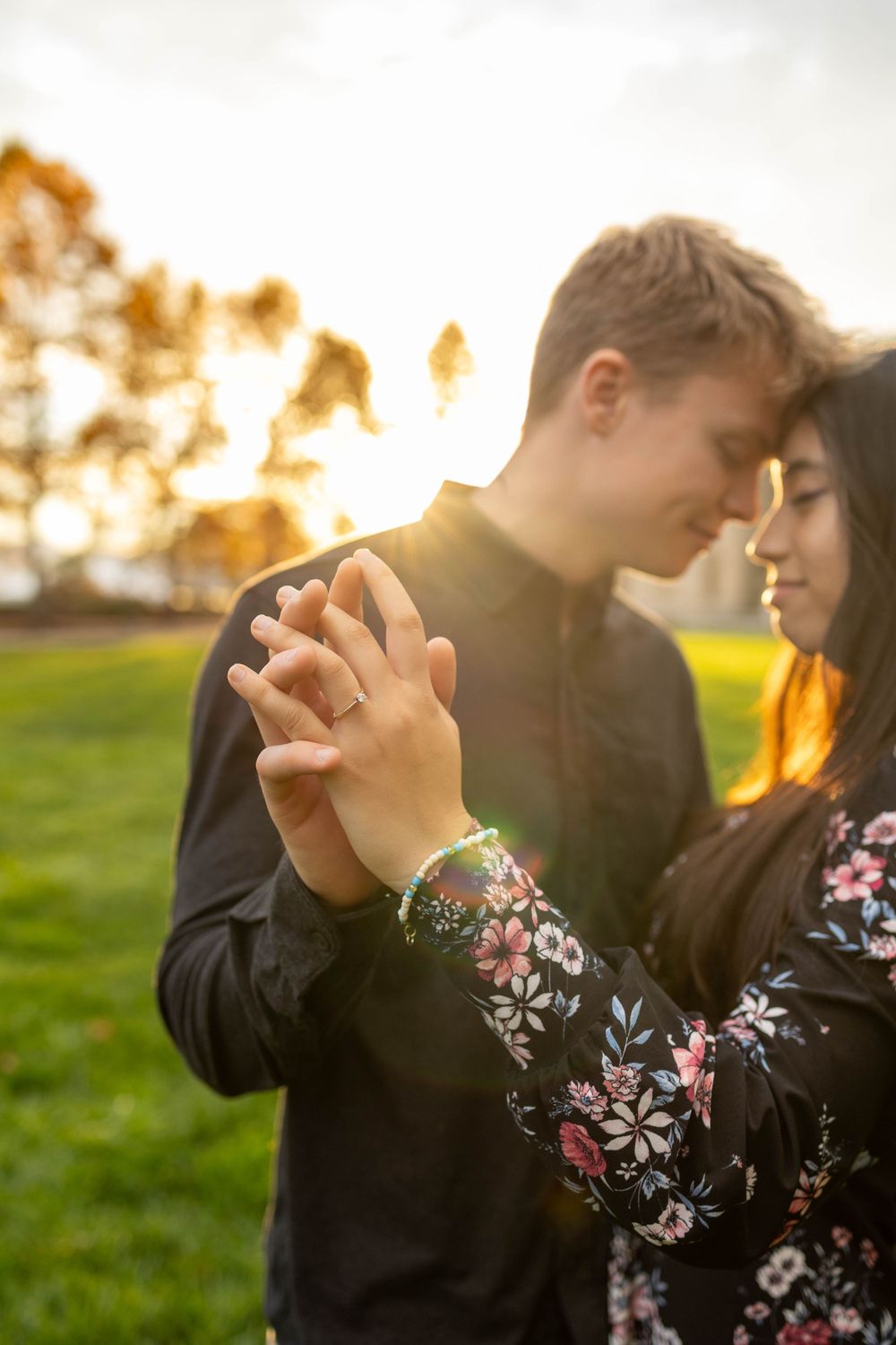Couple sharing intimate moment while dancing in field during golden hour sunset.