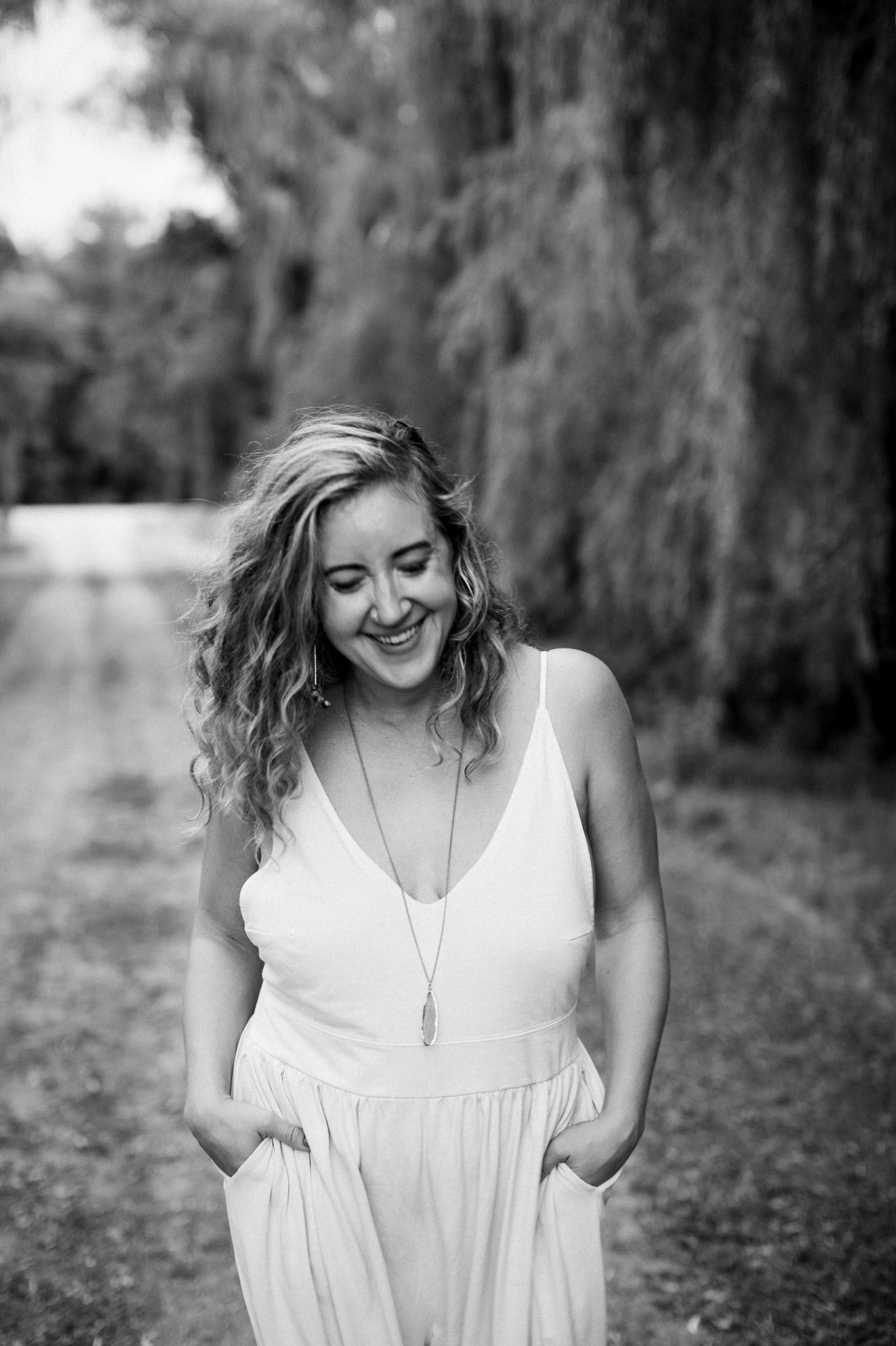 Miranda, the best Twin Cities Family Photographer, gazes downward and laughs while walking down a dirt road in Jordan, MN