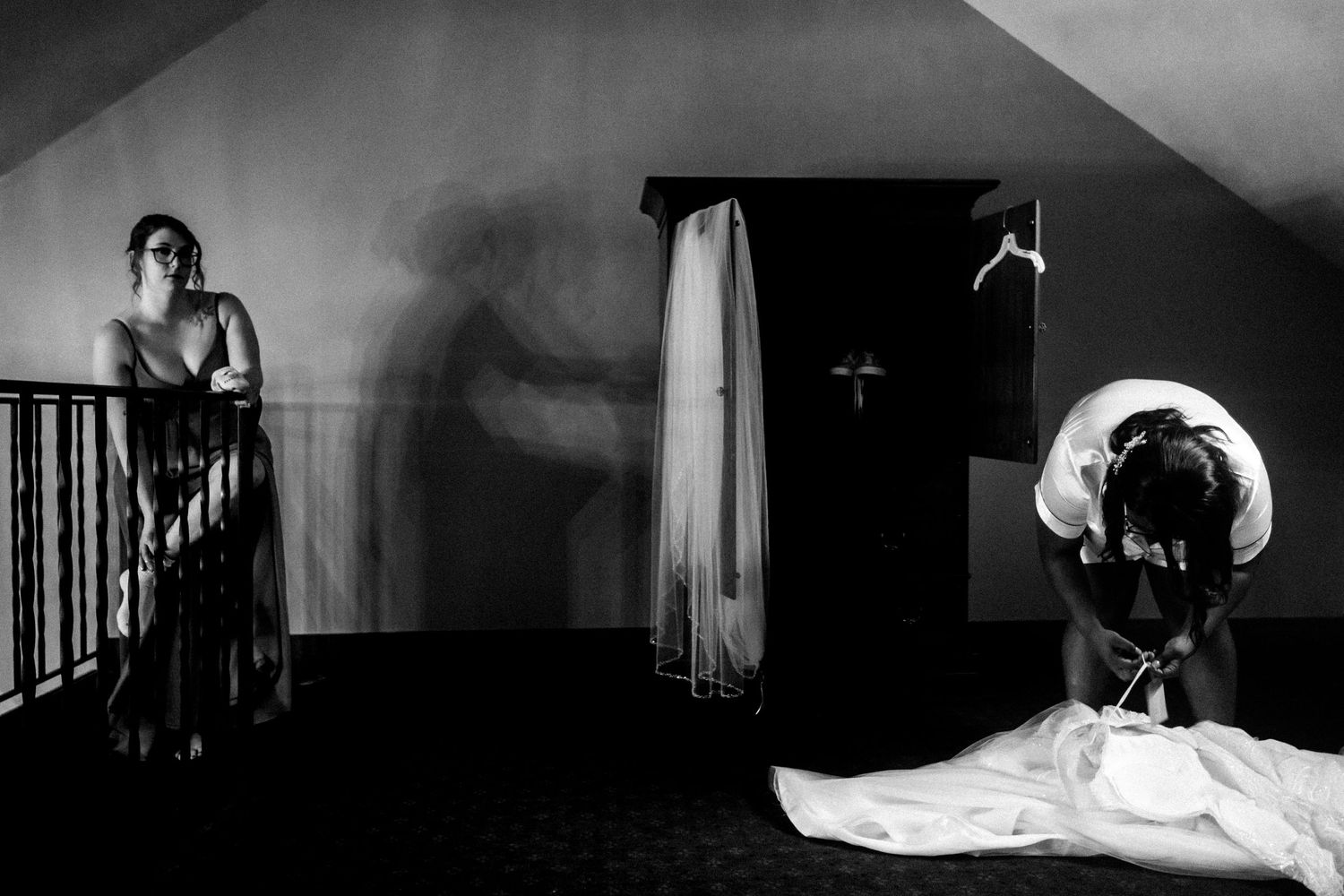 Dramatic black and white photograph with silhouettes and shadows in an attic or upstairs space.