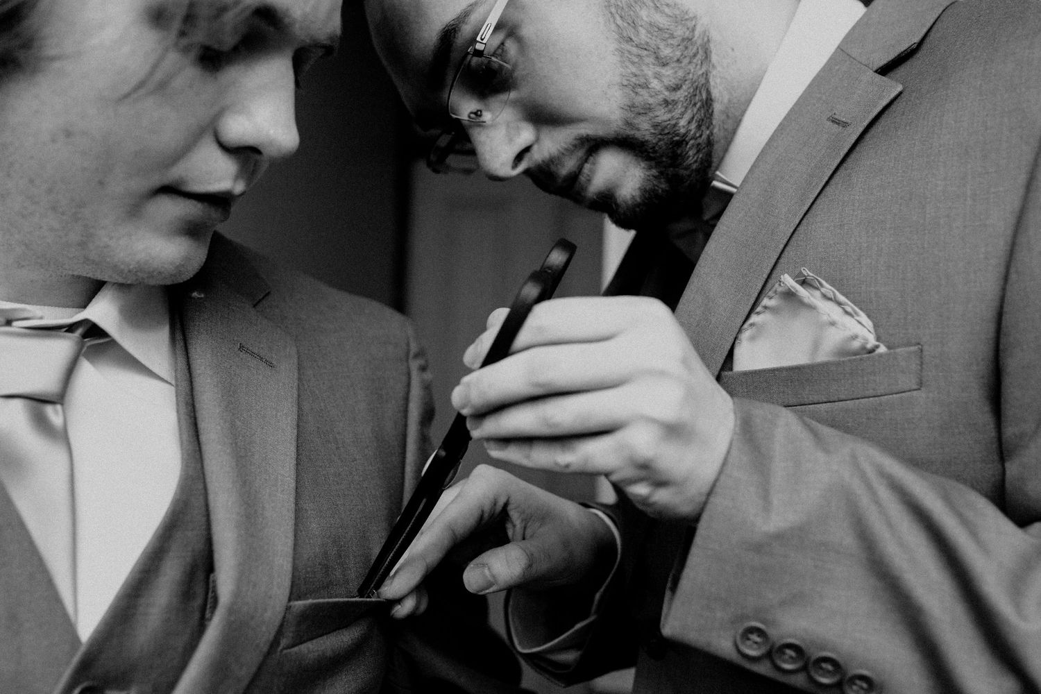 A black and white close-up of someone adjusting a tie or collar.