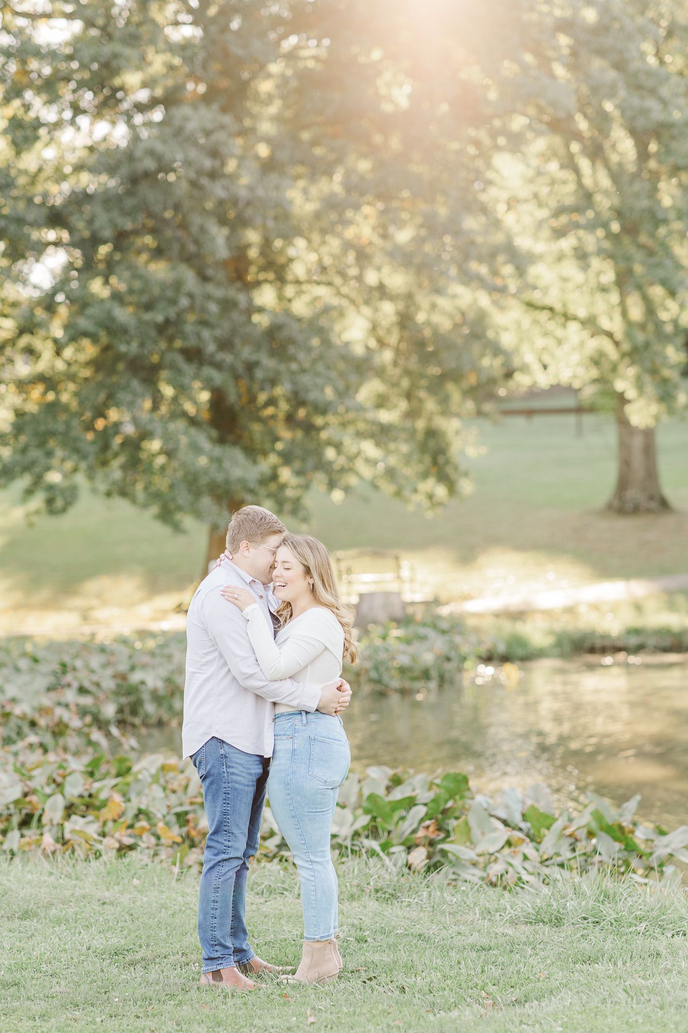 Romantic outdoor engagement photos in a sunlit field with trees in the background.