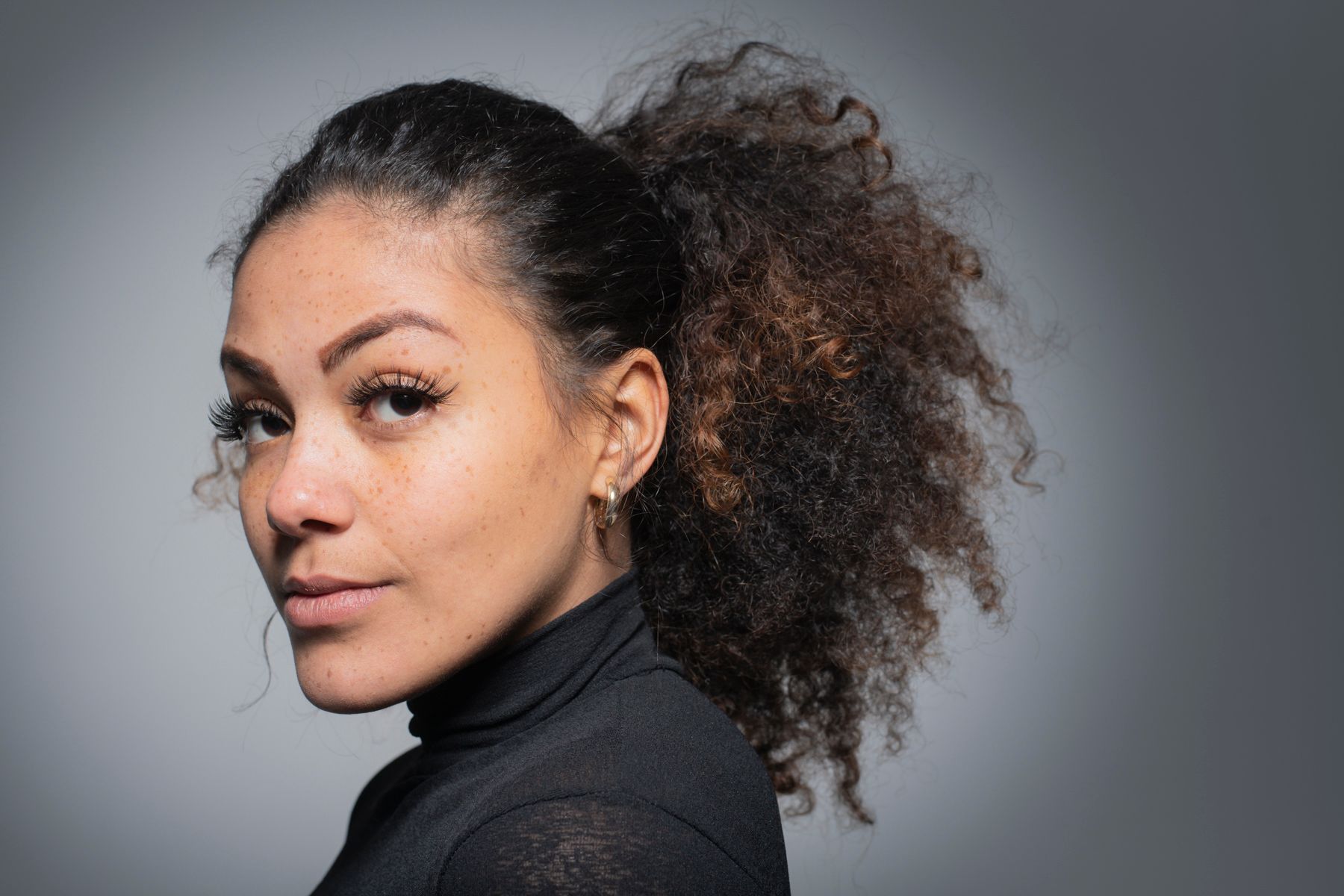 Side profile portrait of young woman with afro hair tied up.