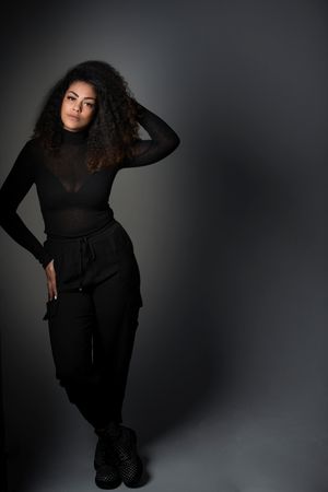 Low key portrait of woman in black running fingers through afro hair.