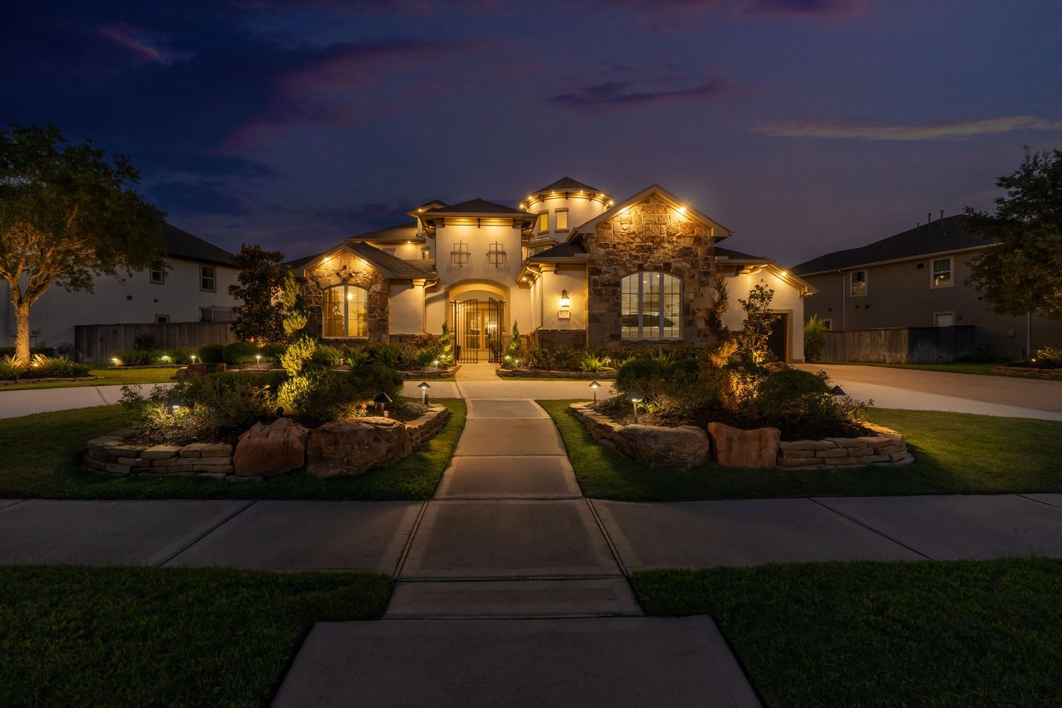 Luxurious home exterior with beautiful landscape lighting at twilight.