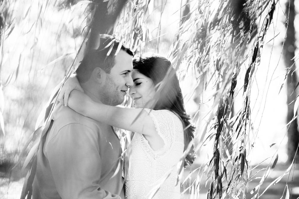 Black and white romantic couple portrait against textured rock wall.