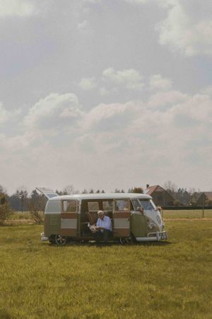 man met volkswagenbus in grasveld