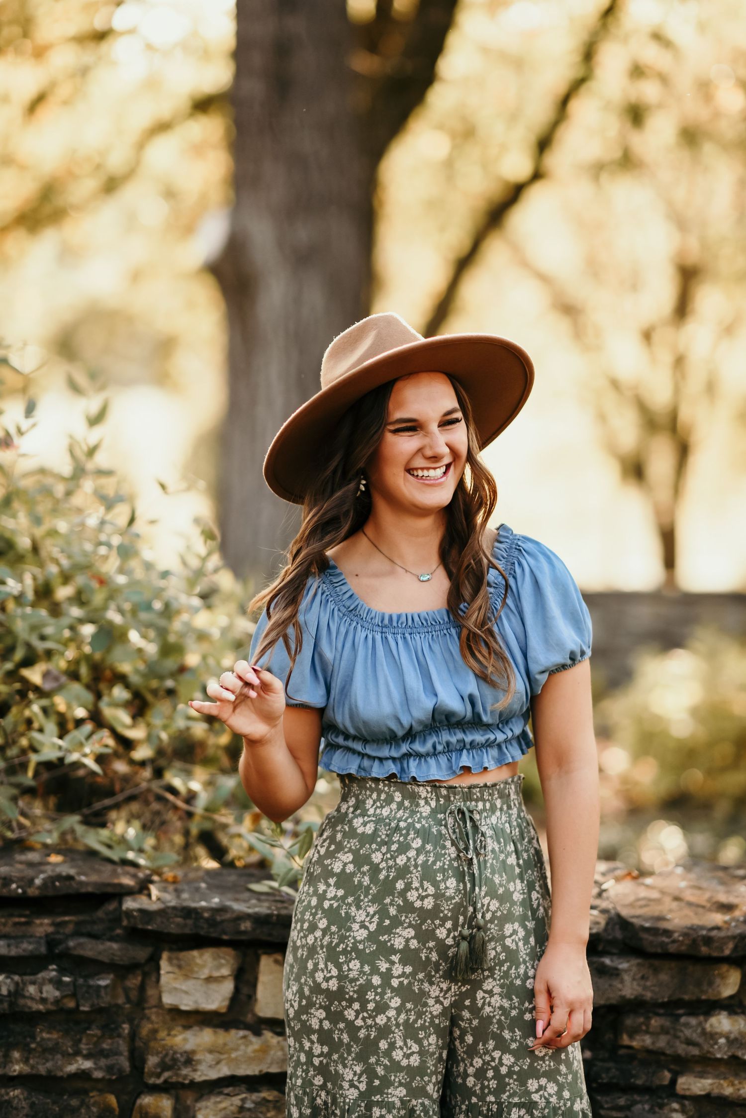 Portrait in golden light featuring western-inspired outfit with blue crop top and floral skirt.