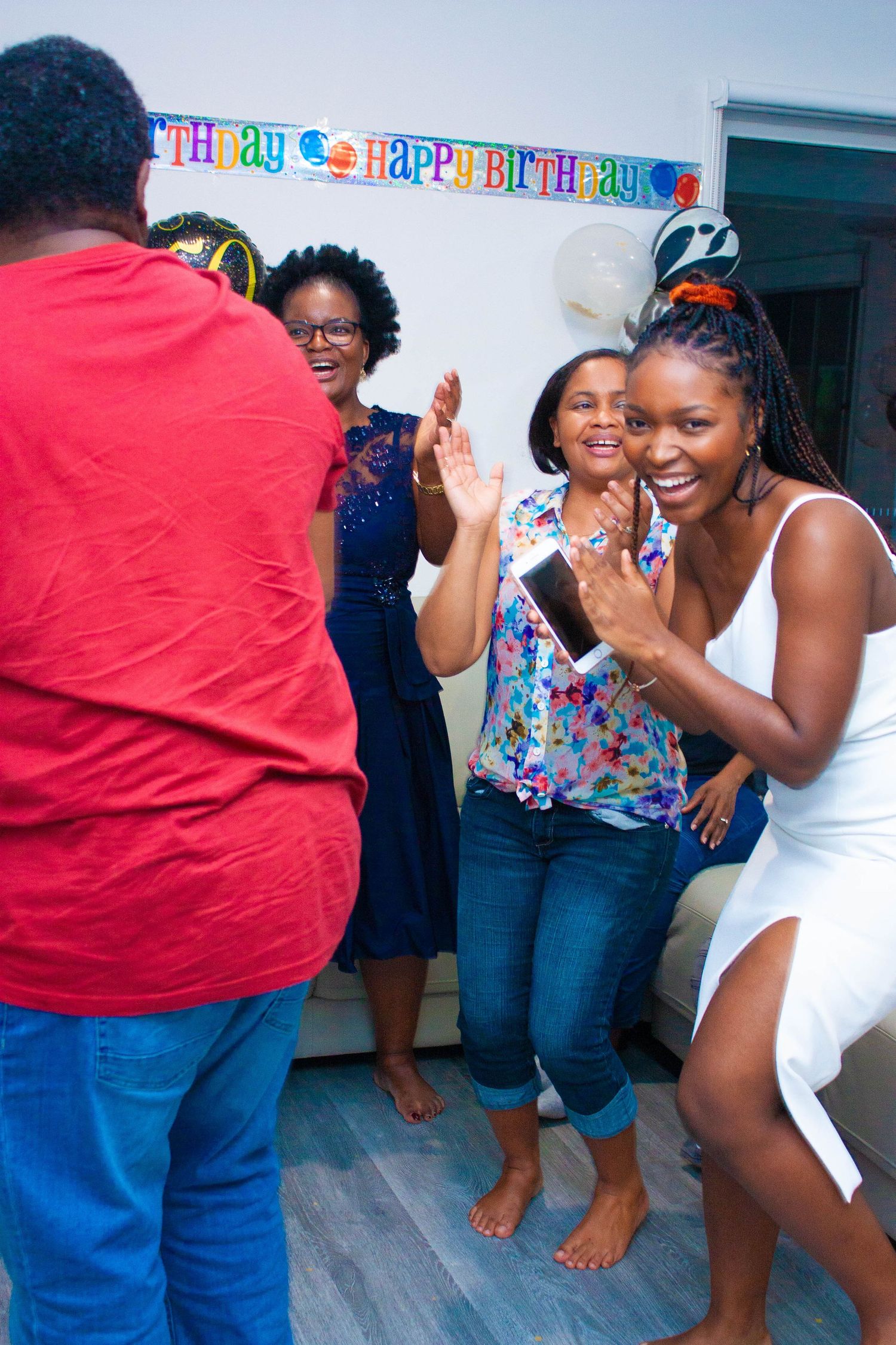 Joyful celebration at a birthday party with people dancing and laughing together.