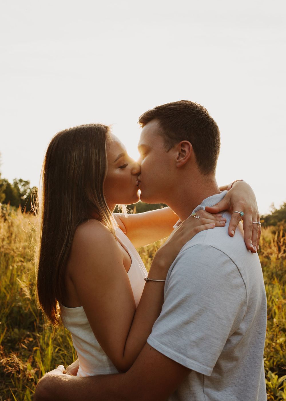 Intimate couple sharing romantic moment in summer meadow at sunset.