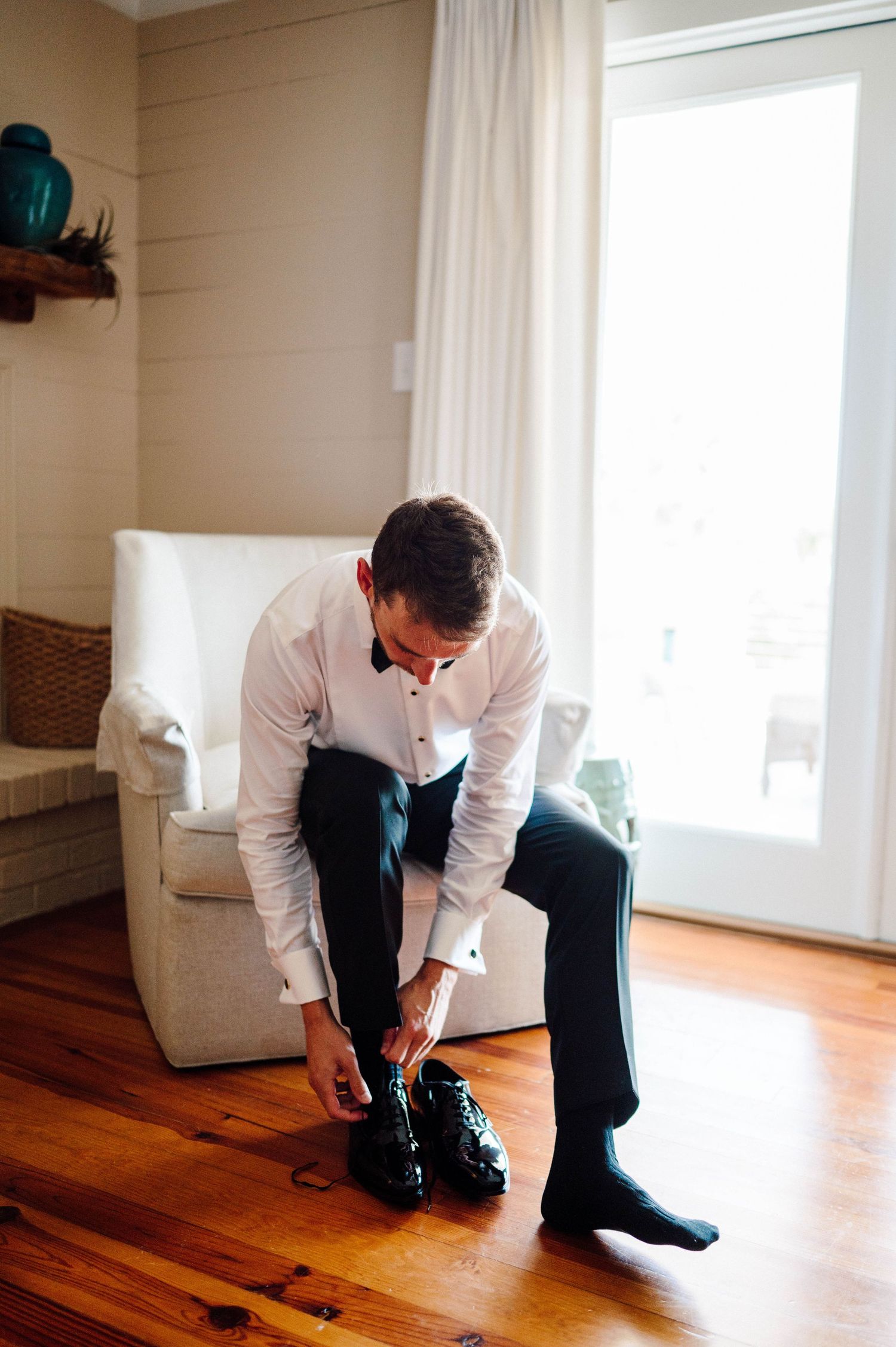 Groom tying his dress shoes for his wedding.