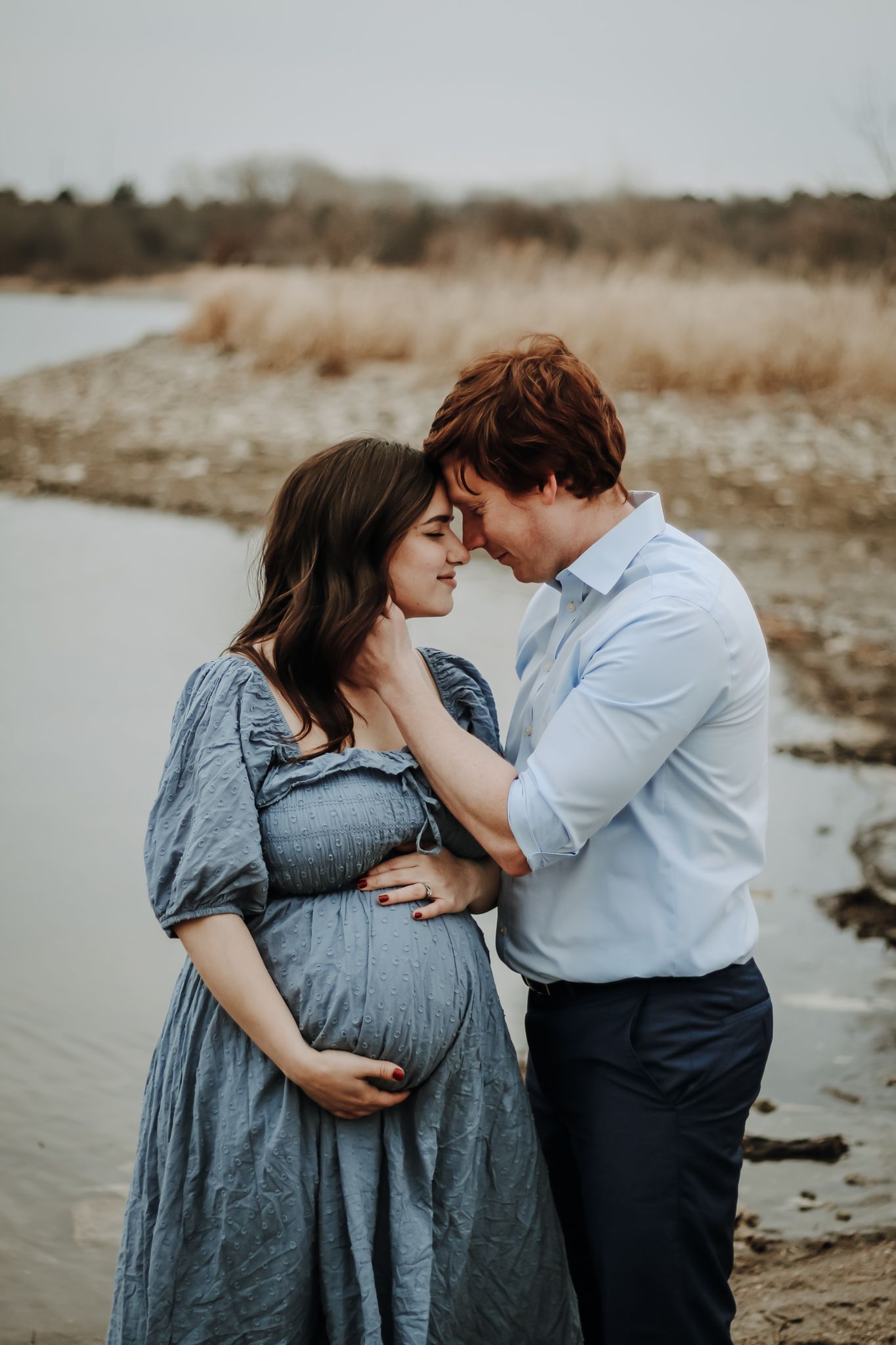 Maternity photoshoot on beach with couple in blue dress and formal wear.