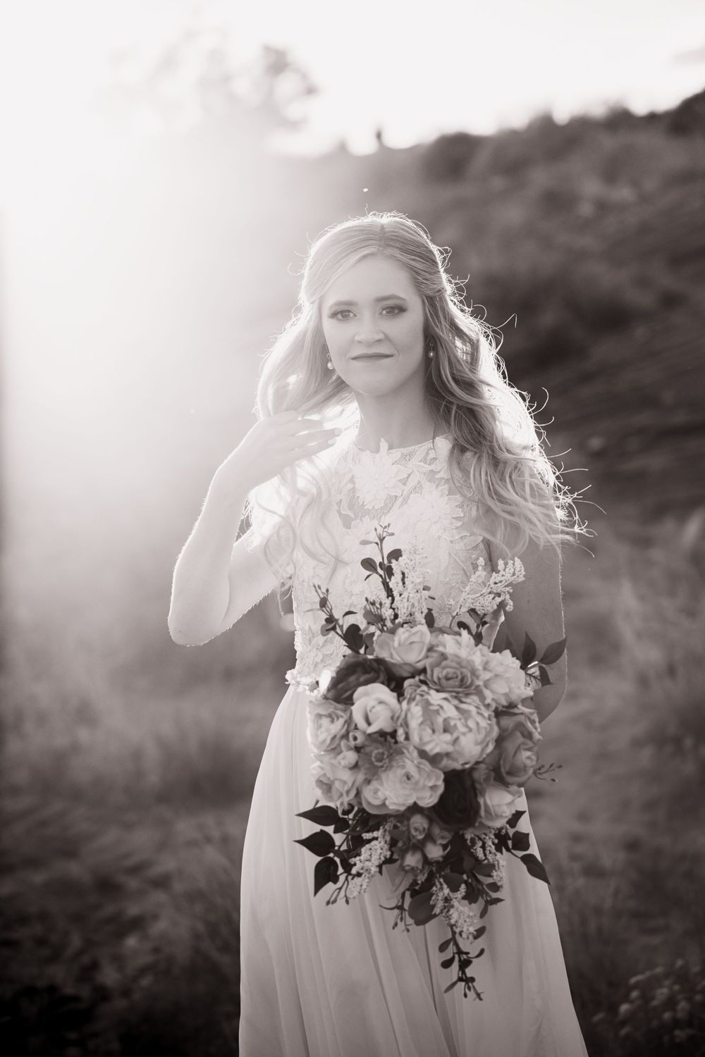 Black and white portrait of blonde bride holding floral bouquet in soft misty outdoor light.