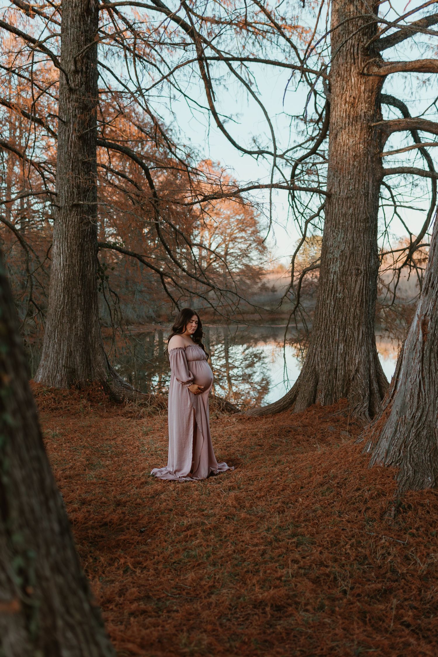 Ethereal scene in autumn forest with person in pink dress near water.