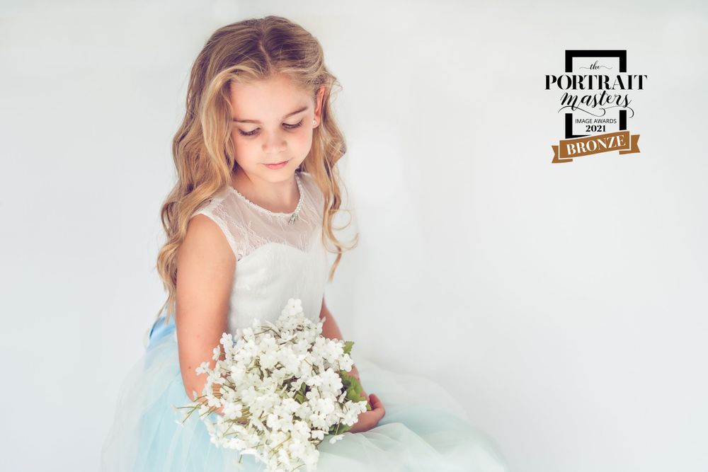 photoshoot of a young girl, studio lighting, flowers, blond hair.